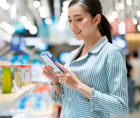 girl in supermarket reading food label off a food product