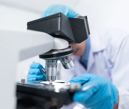 Lab worker looking through a microscope