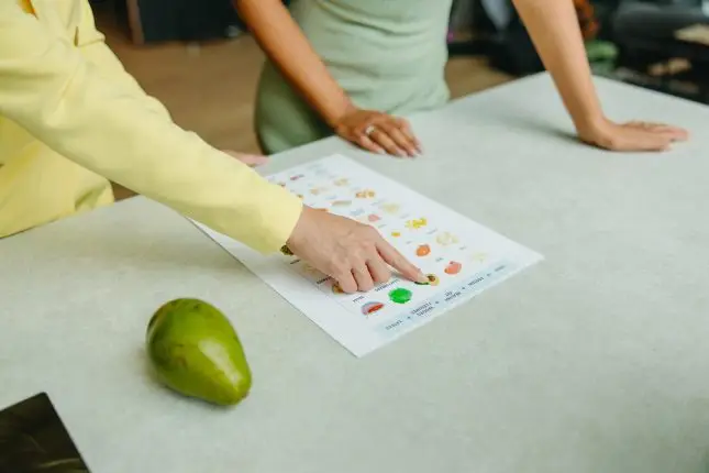 Woman pointinig finger to nutrition table printed on paper